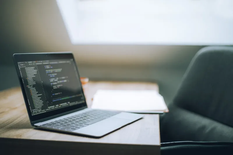 A modern desk workspace with a laptop showing code